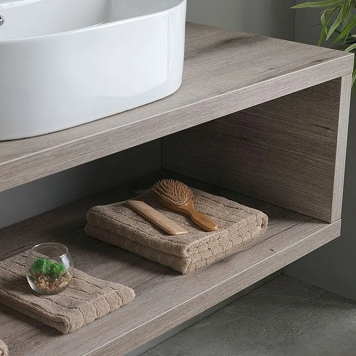 Kiamami Valentina Badmöbel-Set - Braun - Waschtisch aus hellem Holz mit offenen Regalböden und weißem Keramikwaschbecken, mit Handtüchern und Bürste ausgestattet.