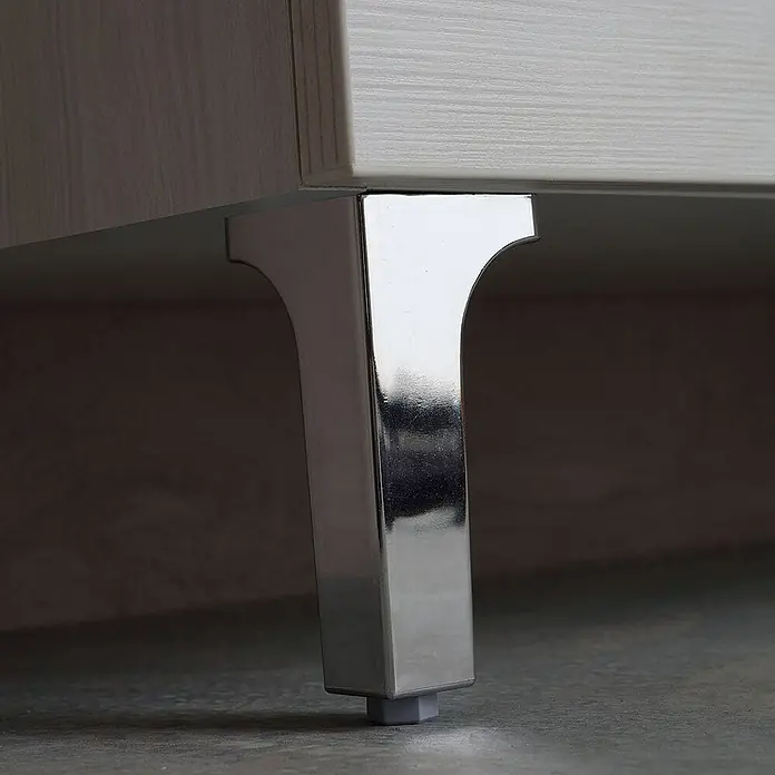 Kiamami Valentina Badmöbel-Set - Helles Holz - Verchromtes Möbelbein stützt einen hellen Holzschrank, mit grauem Bodengleiter.