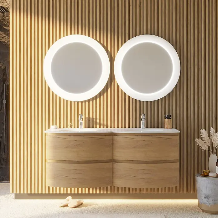 Kiamami Valentina Badmöbel-Set - Holz mittel - Modernes Doppelwaschbecken aus hellem Holz mit weißen Spülen und zwei runden beleuchteten Spiegeln vor einer Lattenwand.