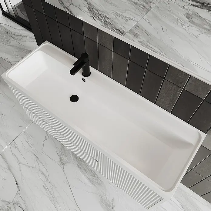 Kiamami Valentina Badmöbel-Set - Weiß - Weißer rechteckiger Badwaschtisch mit integriertem Waschbecken, schwarzem Wasserhahn und gerillter Schrankfront.