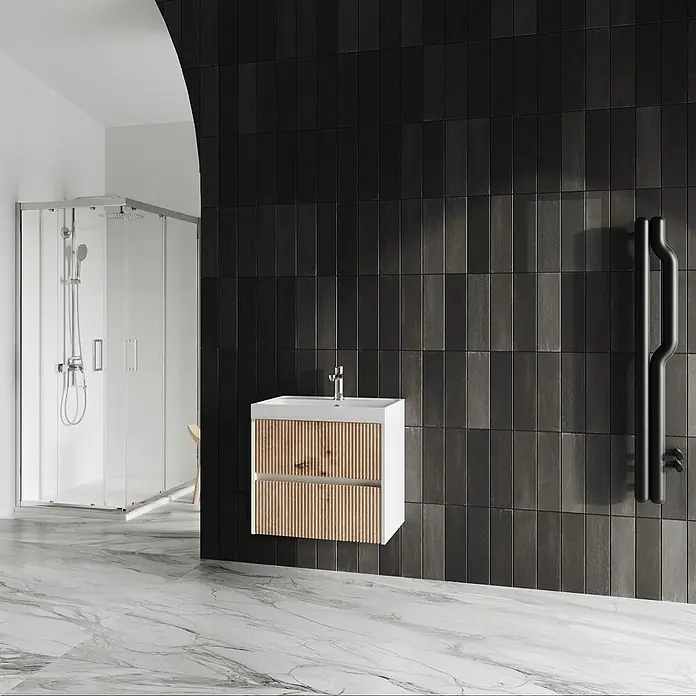 Kiamami Valentina Badmöbel-Set - Braun - Moderner Badezimmer-Waschtisch mit weißem Rahmen und hellen Holzlamellen-Schubladen, montiert an einer schwarzen Fliesenwand.
