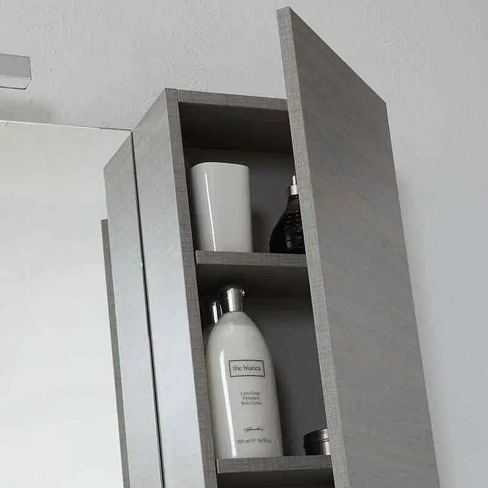 Kiamami Valentina Badmöbel-Set - Grau - Grauer Badezimmer-Wandschrank in Holzoptik mit offener Tür, zeigt Regalböden mit Kosmetikflaschen.
