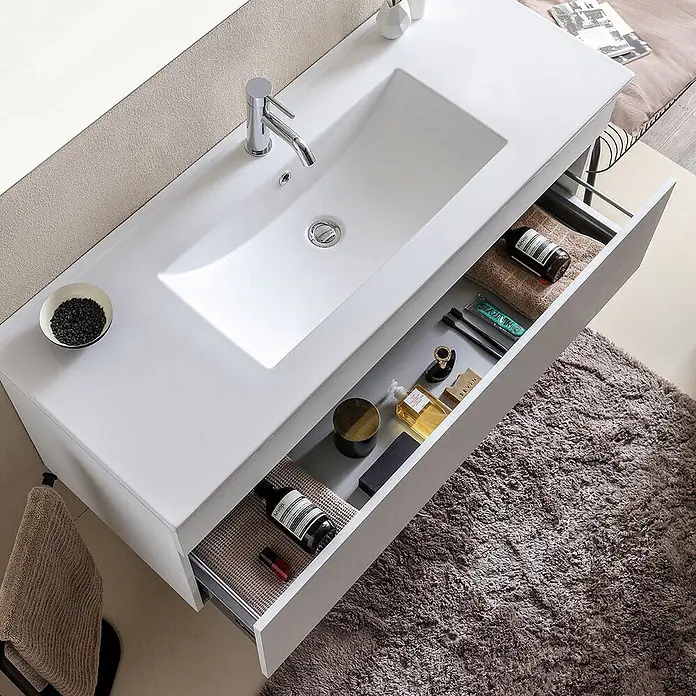 Kiamami Valentina Badmöbel-Set - Weiß - Weißer Badwaschtisch mit integriertem Waschbecken und teilweise geöffneter Schublade, die organisierte Toilettenartikel zeigt.
