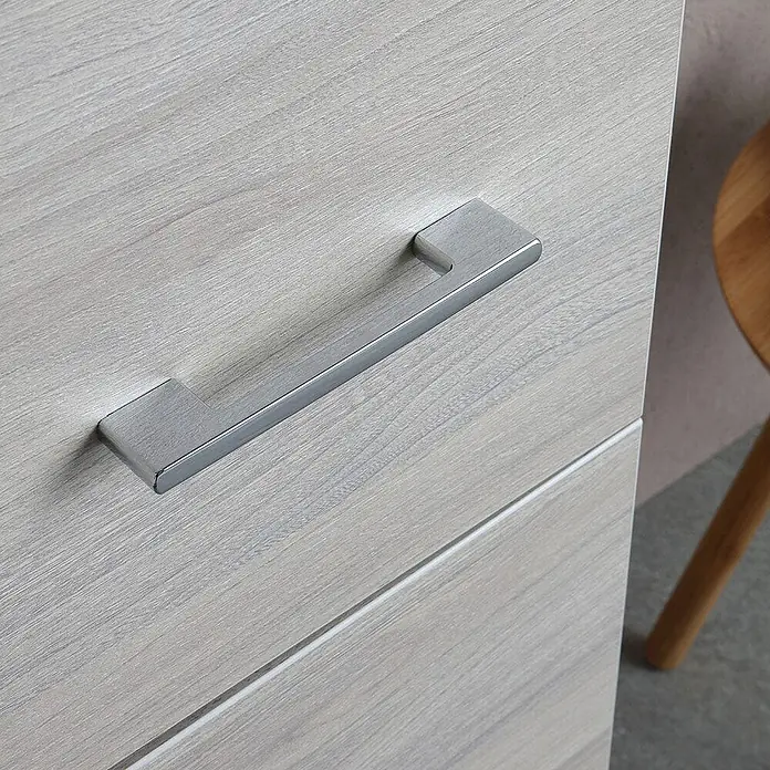 Kiamami Valentina Badmöbel-Set - Grau - Moderner Griff aus gebürstetem Silbermetall an einer hellen Holzschublade.