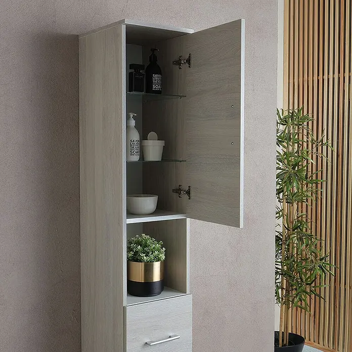Kiamami Valentina Badmöbel-Set - Grau - Hoher, heller Holz-Badezimmerschrank mit offener Tür, Glasböden für Toilettenartikel und offener Ablage mit Pflanze.