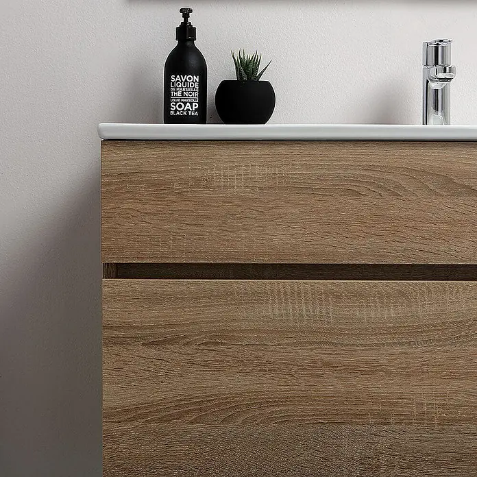 Kiamami Valentina Badmöbel-Set - Helles Holz - Heller Holzoptik-Badezimmerschrank mit weißem Waschbecken, zwei Schubladen, Chromarmatur, Seife und Pflanze.