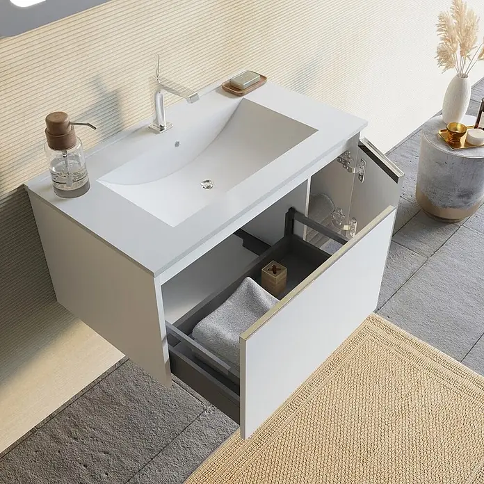 Kiamami Valentina Badmöbel-Set - Weiß - Weißer wandmontierter Badezimmerschrank mit integriertem Waschbecken, Chromarmatur und geöffneter Schublade mit gefaltetem Handtuch.