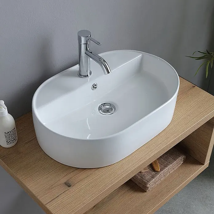 Kiamami Valentina Badmöbel-Set - Braun - Weißes ovales Keramik-Aufsatzwaschbecken mit Chromarmatur auf einer hellen Holzwaschtischplatte.
