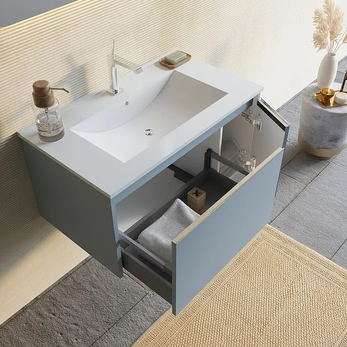 Kiamami Valentina Badmöbel-Set - Hellblau - Hellblauer Badezimmerschrank mit weißem Waschbecken, geöffneter Schublade mit Handtuch und Seifenspender.