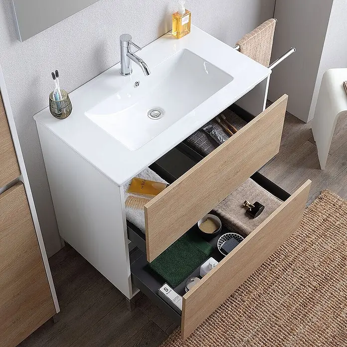 Kiamami Valentina Badmöbel-Set - Helles Holz - Weißer Badunterschrank mit Keramikwaschbecken und Chromarmatur. Zwei offene Schubladen in Holzoptik zeigen organisierten Stauraum für Badutensilien.