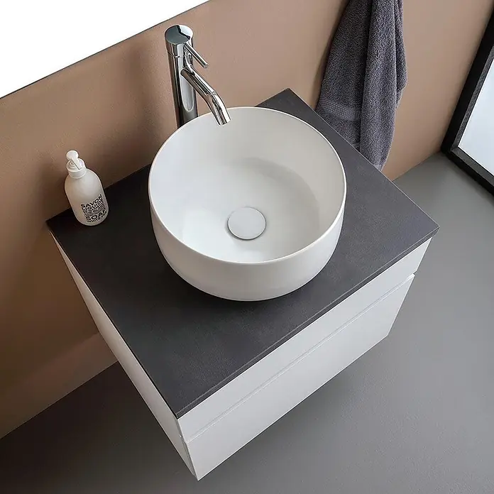 Kiamami Valentina Badmöbel-Set - Weiß - Moderner Badezimmer-Waschtisch mit dunkelgrauer Platte, weißen Schränken, weißem Aufsatzwaschbecken und Chromarmatur.