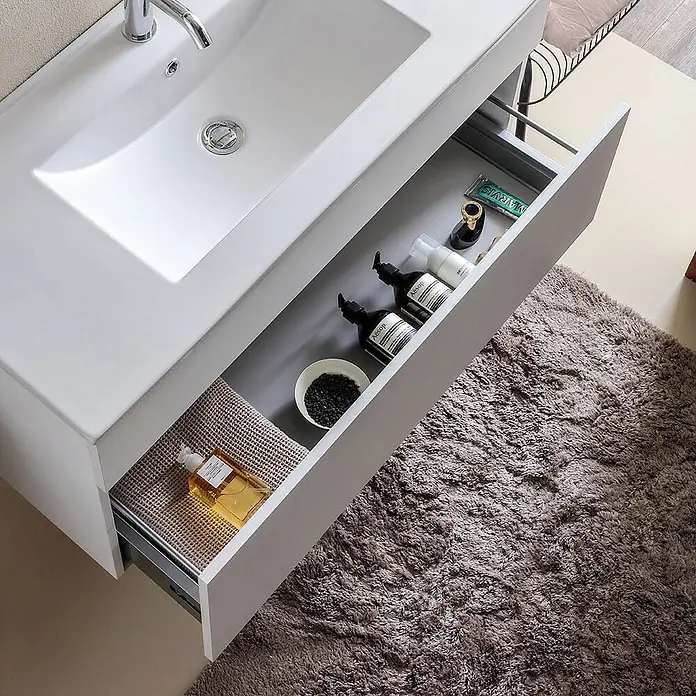 Kiamami Valentina Badmöbel-Set - Weiß - Weißer Badwaschtisch mit integriertem Waschbecken und offener Schublade mit Toilettenartikeln. Grauer Schubladeninnenraum.