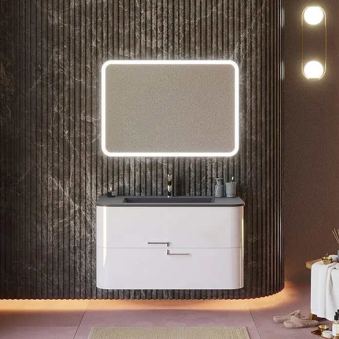 Kiamami Valentina Badmöbel-Set - Weiß - Weißer schwebender Badschrank mit dunkelgrauem Waschbecken und beleuchtetem Spiegel vor dunkler geriffelter Marmorwand.