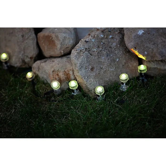 Ledvance Smart+ LED-Panel Gardenspot Mini RGBW 3ST - Dimmbarkeit: Dimmbar, Durchmesser: 23 mm, Leuchtmittel: LED, IP65, II - Warmweiße LED-Gartenleuchten mit klarem Gehäuse beleuchten grünen Rasen an einer Steinmauer.