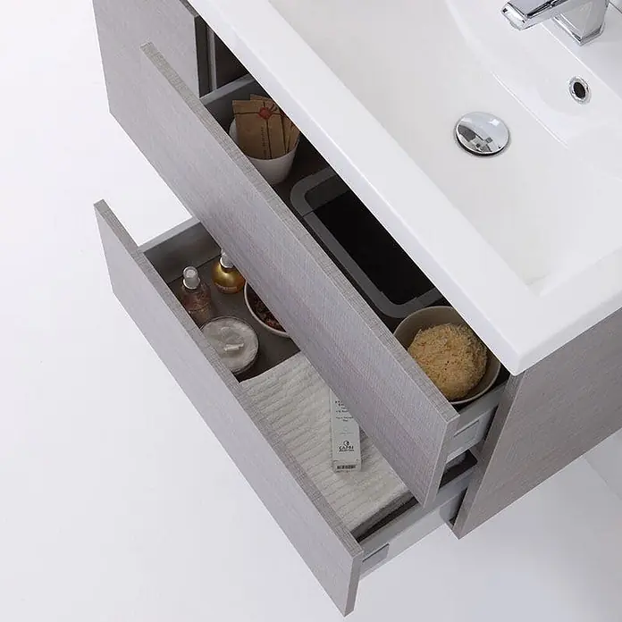 Kiamami Valentina Badmöbel-Set - Grau - Helles graues Badmöbel in Holzoptik mit zwei geöffneten Schubladen und weißem Waschbecken.