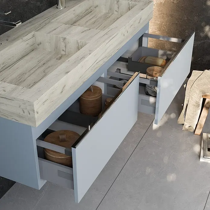 Kiamami Valentina Badmöbel-Set - Hellblau - Moderner Badunterschrank mit integriertem Waschbecken in heller Holzoptik und offenen hellblauen Schubladen, die organisierte Aufbewahrung zeigen.