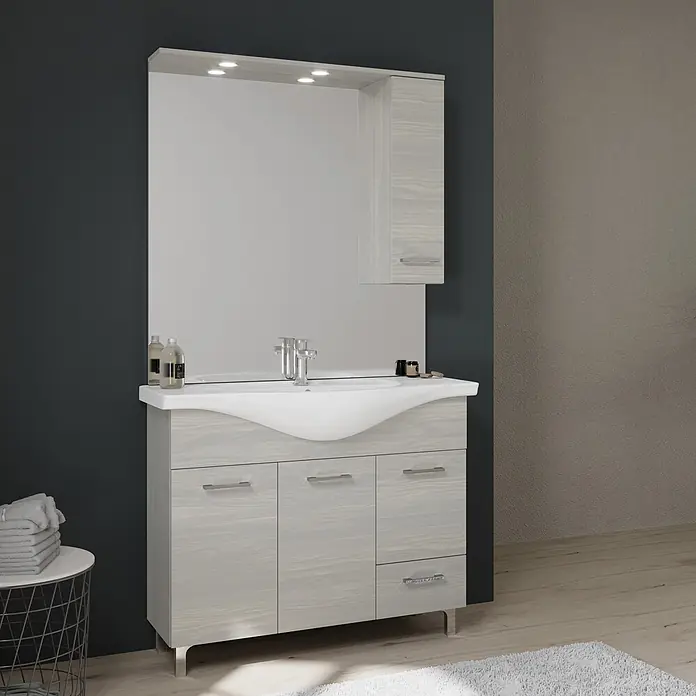 Kiamami Valentina Badmöbel-Set - Helles Holz - Badezimmerschrank aus hellem Holzmaserung mit weißem Waschbecken, Spiegel und integriertem Spiegelschrank mit Beleuchtung in einem modernen Bad.