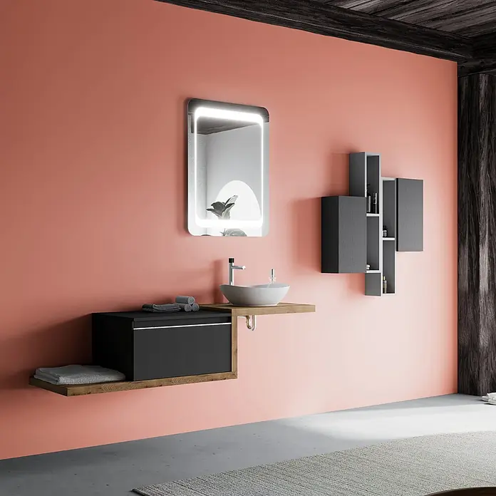 Kiamami Valentina Badmöbel-Set - Grau - Moderne Badkombination in Schwarz und Holz mit weißem Waschbecken, Chromarmatur, beleuchtetem Spiegel und grauen Regalen an korallenfarbener Wand.