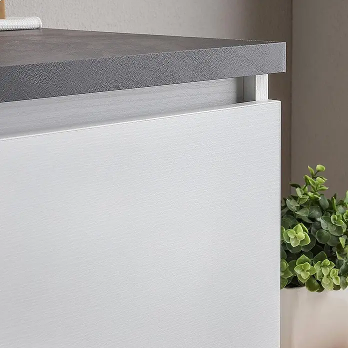 Kiamami Valentina Badmöbel-Set - Weiß - Moderner Schrank mit dunkelgrauer, texturierter Platte und weißer, gemaserter Schubladenfront. Rechts eine Grünpflanze.