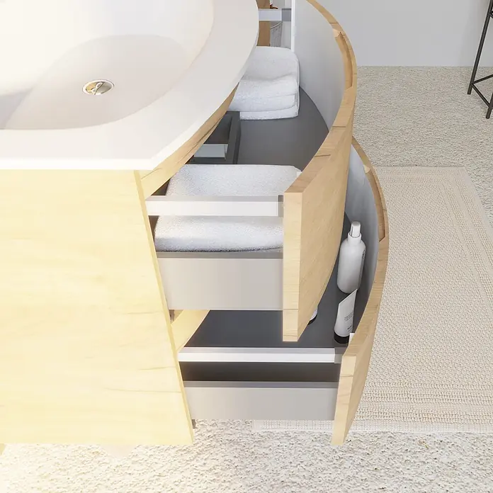 Kiamami Valentina Badmöbel-Set - Holz mittel - Moderner geschwungener Badunterschrank aus hellem Holz mit weißem Waschbecken, offene Schubladen mit Handtüchern und Pflegeprodukten.