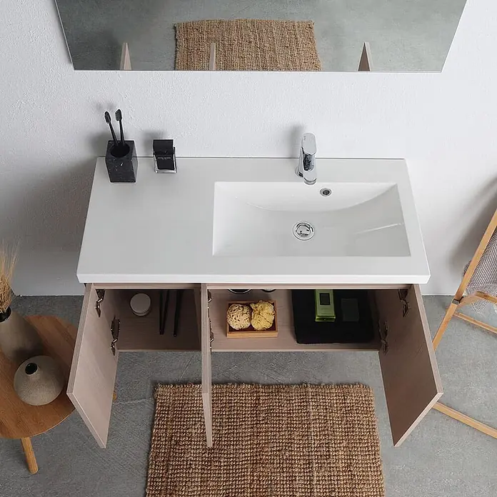 Kiamami Valentina Badmöbel-Set - Beige - Badezimmermöbel mit weißer Arbeitsplatte und integriertem Waschbecken, hellen Holzschränken und offenen Türen, die Stauraum zeigen.