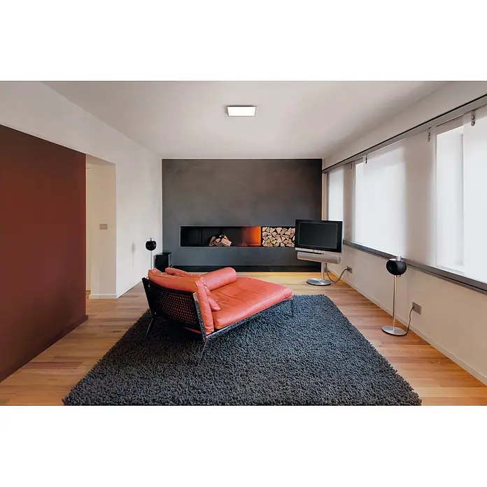 Ledvance Smart+ WiFi LED-Panel Planon Plus - L x B x H: 300 x 300 x 56 mm, Weiß, Warmweiß - Oranger Ledersessel mit schwarzer Netzlehne und Chromrahmen auf dunklem Teppich im modernen Wohnzimmer.