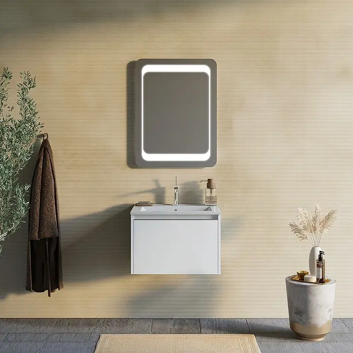 Kiamami Valentina Badmöbel-Set - Weiß - Modernes Badezimmer mit weißem wandmontiertem Waschtisch, silbernem Wasserhahn und beleuchtetem Spiegel mit abgerundeten Ecken.