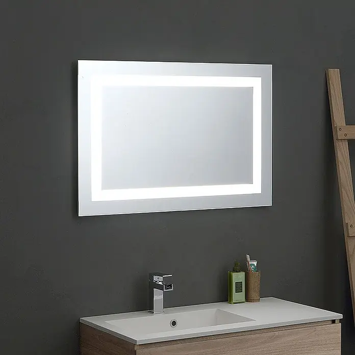 Kiamami Valentina Badmöbel-Set - Helles Holz - Rechteckiger LED-beleuchteter Badezimmerspiegel über einem Waschbecken an dunkler Wand.