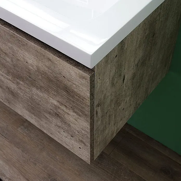 Kiamami Valentina Badmöbel-Set - Zementfarbe - Nahaufnahme eines weißen Keramikwaschbeckens auf einem wandmontierten Waschtisch in distressed Grau-Braun-Holzoptik.