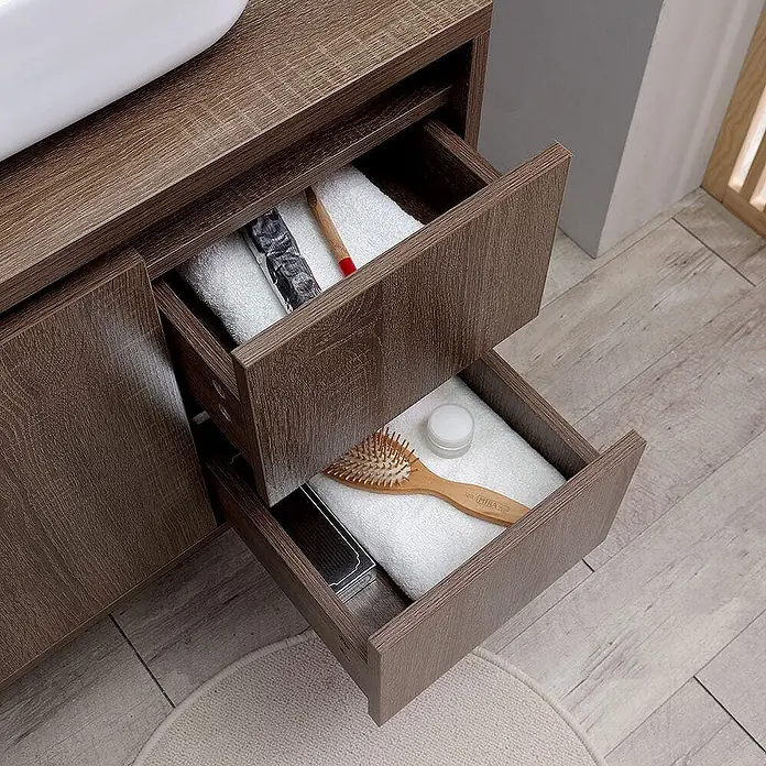 Kiamami Valentina Badmöbel-Set - Holz dunkel - Brauner Badunterschrank in Holzoptik mit zwei geöffneten Schubladen, die Handtücher und Toilettenartikel zeigen.