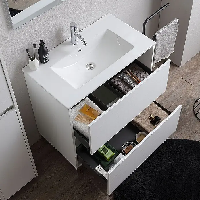 Kiamami Valentina Badmöbel-Set - Weiß - Moderner weißer Badunterschrank mit integriertem Waschbecken und zwei geöffneten Schubladen, die Toilettenartikel zeigen.