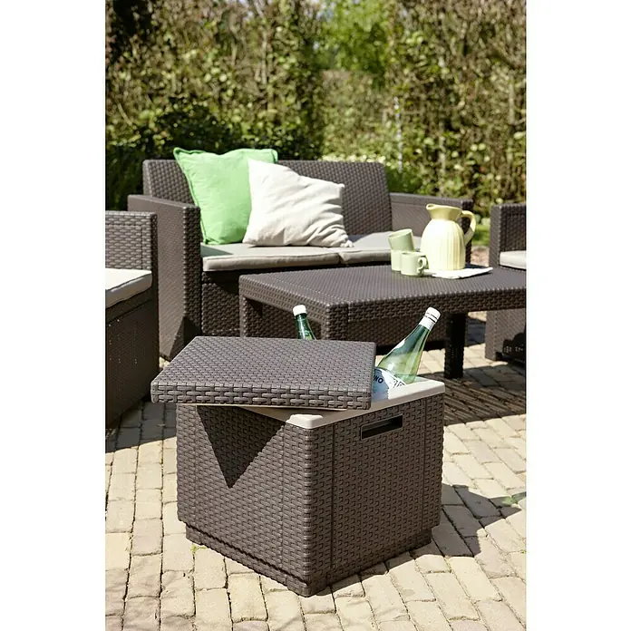 Allibert Nevera de camping Ice Cube - 42 x 42 x 41 cm, Marrón - Escena al aire libre con una nevera de ratán llena de bebidas, parte de un juego de patio con sofá, cojines y mesa para relajarse al aire libre.