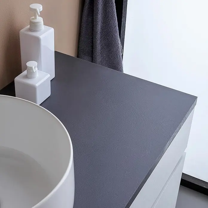 Kiamami Valentina Badmöbel-Set - Weiß - Modernes Badmöbel mit dunkelgrauer Arbeitsplatte und weißem Aufsatzwaschbecken und Seifenspendern.