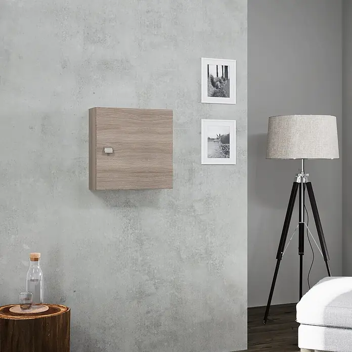 Kiamami Valentina Badmöbel-Set - Holz mittel - Helles Holz-Wandschrank mit silbernem Griff, an einer grauen Wand in einem modernen Raum.