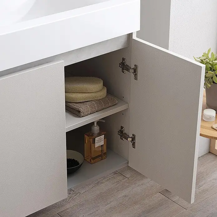 Kiamami Valentina Badmöbel-Set - Grau - Hellesgrauer Badschrank mit geöffneter Tür, der zwei Regale mit Toilettenartikeln zeigt. Weiße Arbeitsplatte darüber.