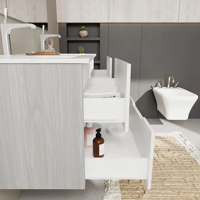 Kiamami Valentina Badmöbel-Set - Weiß - Moderner Badschrank mit heller Holzmaserung und offenen weißen Schubladen, der organisierten Stauraum für Handtücher und Pflegeprodukte zeigt.