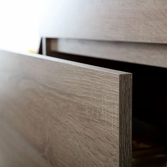 Kiamami Valentina Badmöbel-Set - Helles Holz - Leicht geöffnete Schublade in heller Holzoptik mit sichtbarer Maserung, Teil eines modernen Schranks.