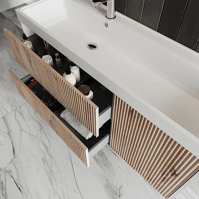 Kiamami Valentina Badmöbel-Set - Braun - Moderner weißer Badezimmerschrank mit langem Waschbecken und geriffelten Echtholzschubladen, zwei Schubladen sind leicht geöffnet.
