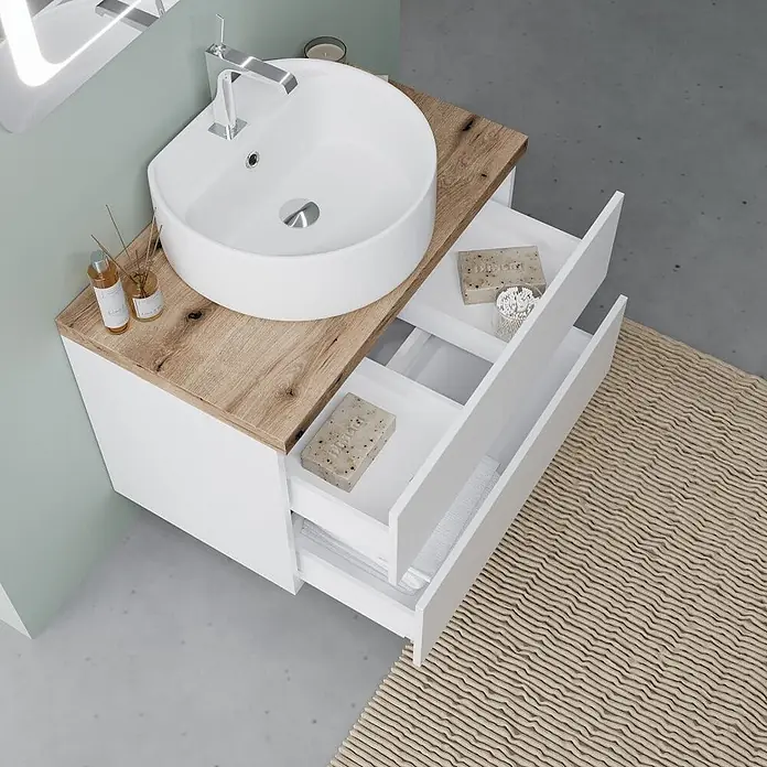 Kiamami Valentina Badmöbel-Set - Weiß - Weißer Badunterschrank mit heller Holzplatte und Aufsatzwaschbecken. Offene Schubladen zeigen Stauraum.