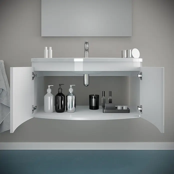 Kiamami Valentina Badmöbel-Set - Weiß - Weißer Badunterschrank mit offenen Türen, der Toilettenartikel auf einem geschwungenen Regal zeigt, integriertem Waschbecken und Chromarmatur.