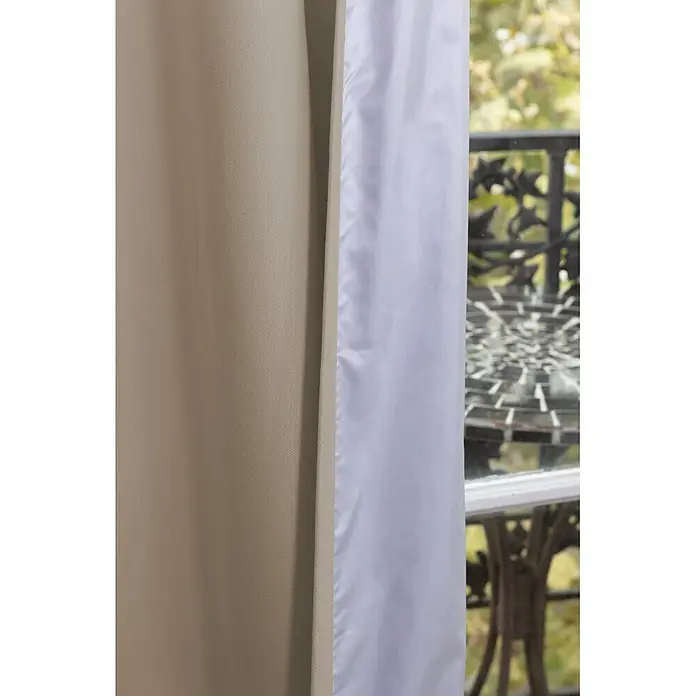 Cortina térmica Cocoon - An x Al: 140 x 260 cm, 100% poliéster, Taupe - Dos cortinas, una beige y una blanca, cubriendo parcialmente una ventana con una vista exterior borrosa.