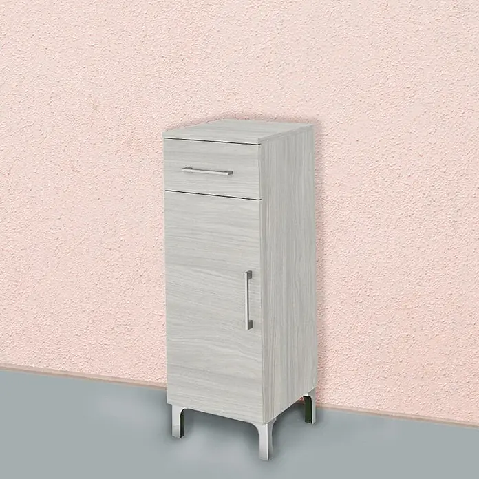 Kiamami Valentina Badmöbel-Set - Grau - Hellgrauer Schrank in Holzoptik mit Schublade, Tür, silbernen Griffen und silbernen Beinen, vor einer rosa Wand.