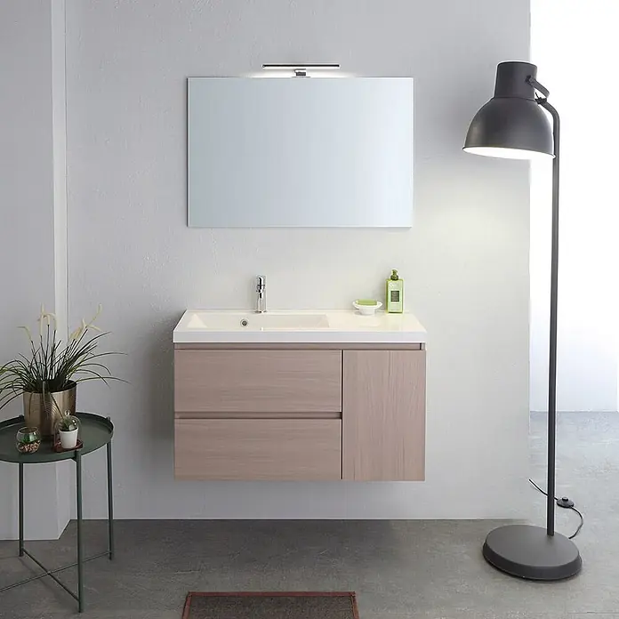 Kiamami Valentina Badmöbel-Set - Beige - Heller Waschtischunterschrank aus Holz mit weißem Waschbecken und Arbeitsplatte, zwei Schubladen und einem Seitenfach unter einem Spiegel.