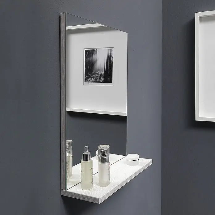 Kiamami Valentina Badmöbel-Set - Grau - Wandspiegel mit integrierter weißer Regalablage in Holzoptik, auf der Kosmetikflaschen stehen.