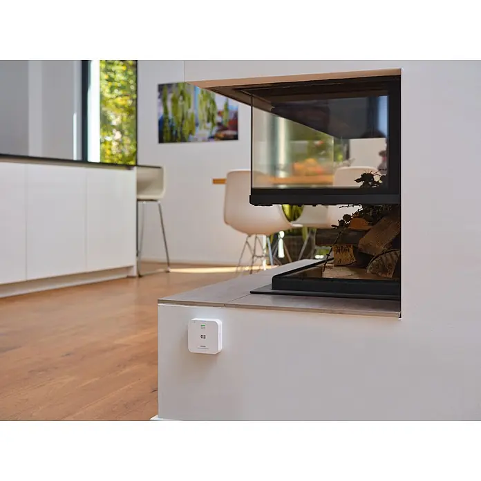 Ledvance Smart+ WiFi Kohlenmonoxidmelder - L x B x H: 8,5 x 2,73 x 8,5 cm, Batterielaufzeit: 5 Jahre - Weißer rechteckiger Kohlenmonoxidmelder an einer Wand neben einem modernen Kamin, der Sicherheit im Zuhause gewährleistet.