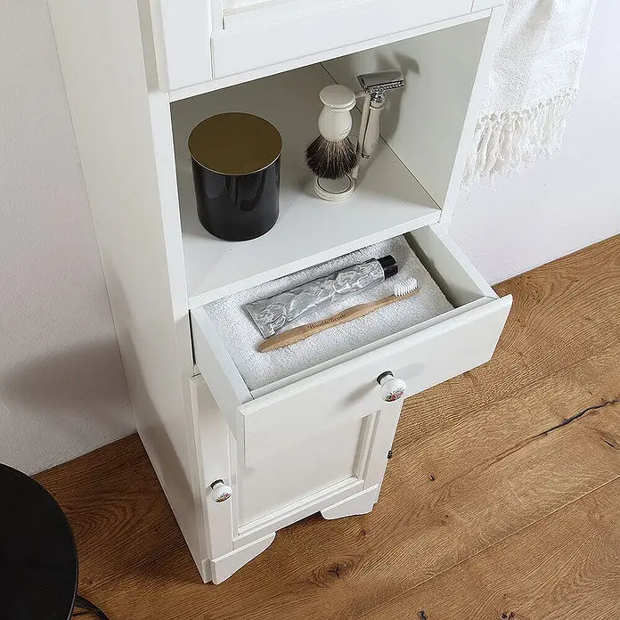 Kiamami Valentina Badmöbel-Set - Weiß - Weißer Badhochschrank mit offener Ablage und Schublade, gefüllt mit Toilettenartikeln. Mit dekorativen Blumenknäufen.