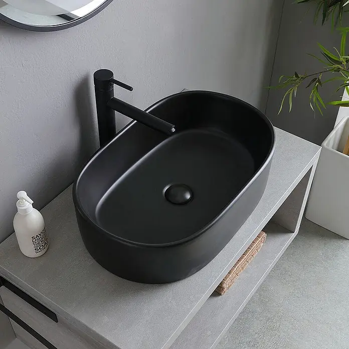 Kiamami Valentina Badmöbel-Set - Grau - Matt-schwarzes Keramik-Aufsatzwaschbecken mit passendem schwarzem Wasserhahn auf hellgrauem Waschtisch.