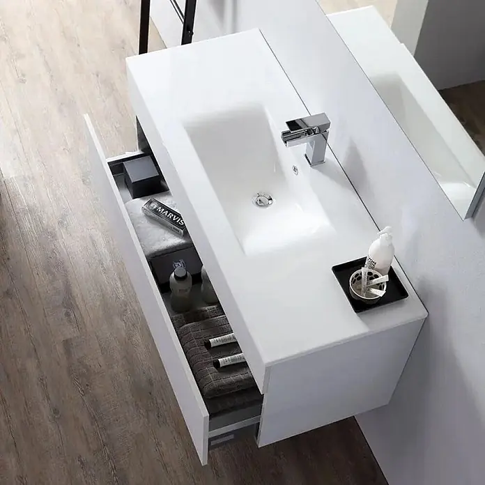 Kiamami Valentina Badmöbel-Set - Grau - Weißer schwebender Badezimmerschrank mit integriertem Waschbecken und offener Schublade, die Toilettenartikel und Handtücher zeigt.