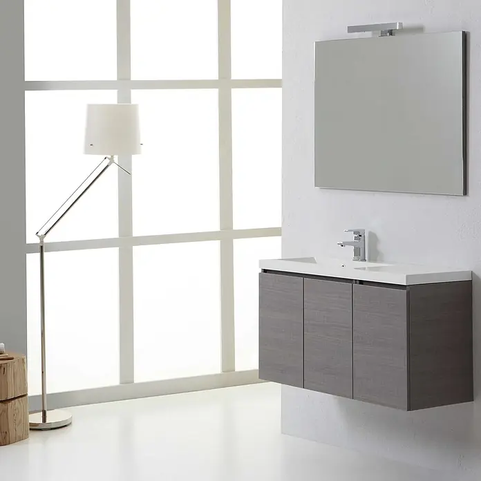 Kiamami Valentina Badmöbel-Set - Grau - Moderne schwebende Badmöbel in Grauholzoptik mit weißem Waschbecken, Chromarmatur, Spiegel und Leuchte in hellem Bad.