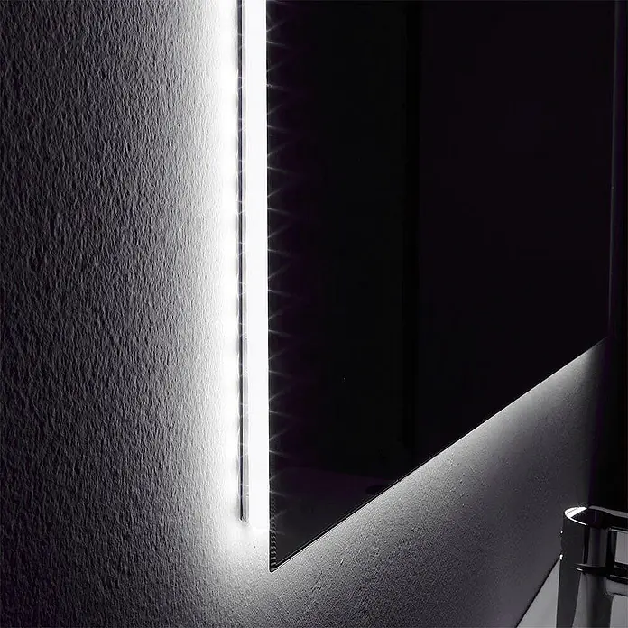 Kiamami Valentina Badmöbel-Set - Helles Holz - Vertikaler LED-Lichtstreifen an einem Spiegel beleuchtet eine strukturierte Wand und den Waschbeckenbereich. Schafft Ambiente- und Arbeitsbeleuchtung.